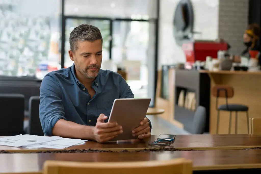 Man reading tablet at coffee shop table