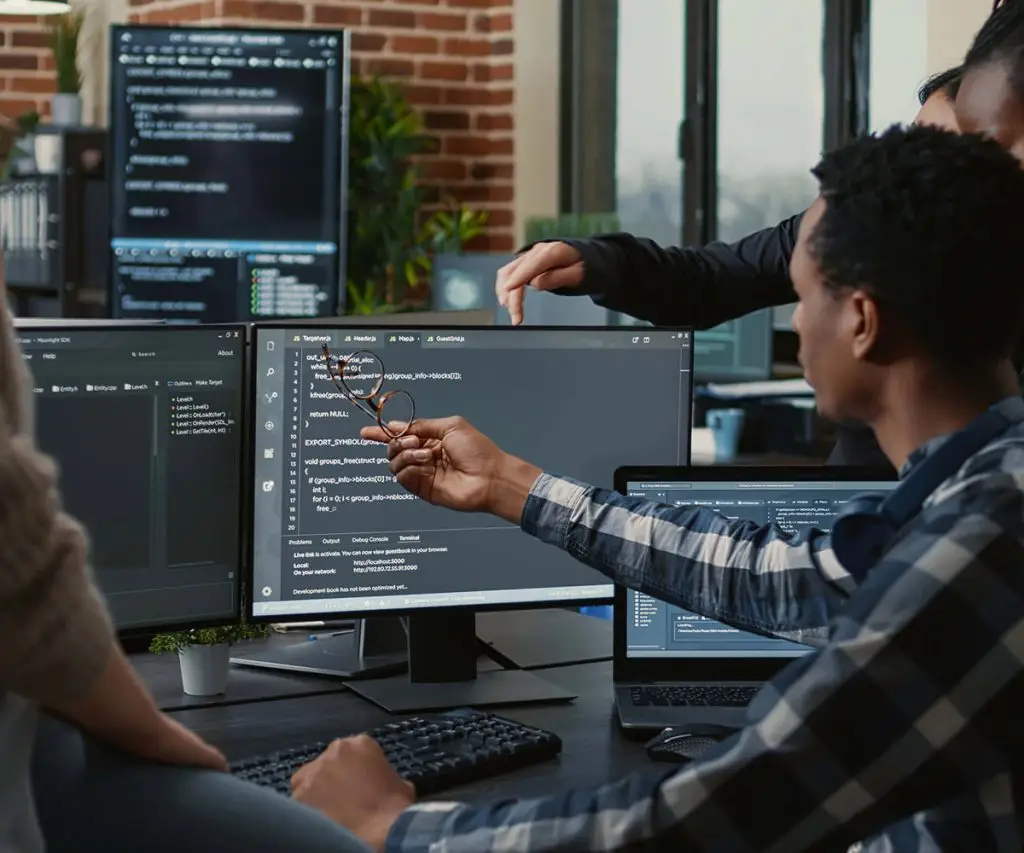 Group of colleagues looking at computer monitors with code on them